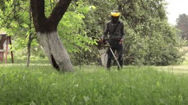 Elinde çim biçme makinesiyle evin önünde çim biçen bir işçi. Bir adamın ellerinde budayıcı. Bahçıvan çimleri biçiyor. Yaşam biçimi.