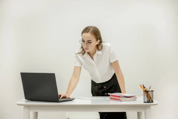 Beautiful secretary in spectacles is checking her boss is meeting to arrange another one. She is friendly and smiling.