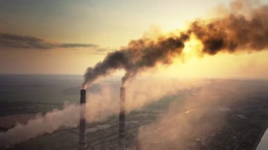 Kömür santralinin hava manzarası siyah dumanlı yüksek borular gün batımında atmosferi kirletiyor.