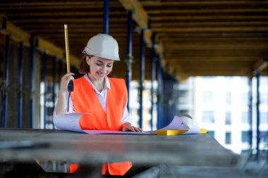 Mimar ya da mühendis, bina inşaatı projesini bina içinde ayrıntılı bir planla inceliyor. Kadın inşaat mühendisleri veya mimarlar çalışan insanlar.