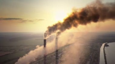 Kömür santralinin hava manzarası siyah dumanlı yüksek borular gün batımında atmosferi kirletiyor