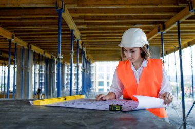 Şablon planıyla inşaat alanının içinde çalışan, gezinen mimar veya mühendis.