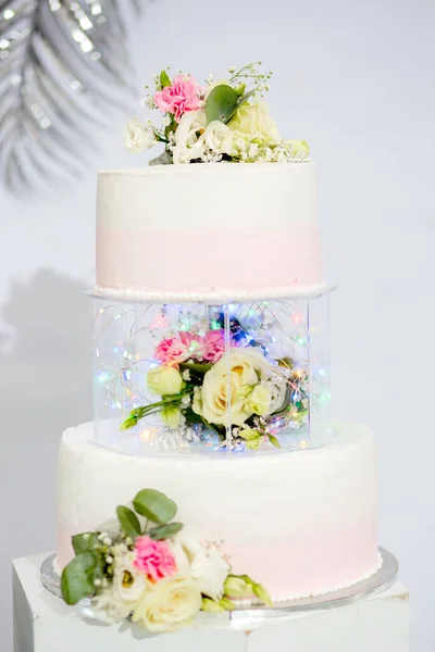 Tiered cake for wedding or birthday. Beautiful white and pink festive cake decorated with flowers