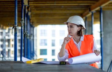 Mimar, monolitik bir inşaat sahasında proje planını düşündü.