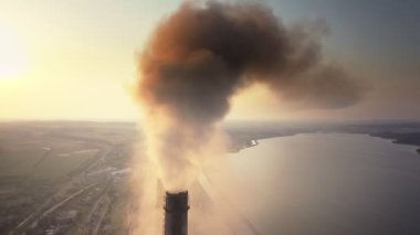 Kömür santralinin hava manzarası siyah dumanlı yüksek borular gün batımında atmosferi kirletiyor