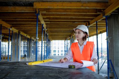 Şablon planıyla inşaat alanının içinde çalışan, gezinen mimar veya mühendis.