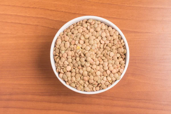 Lentilhas cruas em uma tigela sobre uma mesa de madeira. (Lente culinaris ) — Fotografia de Stock