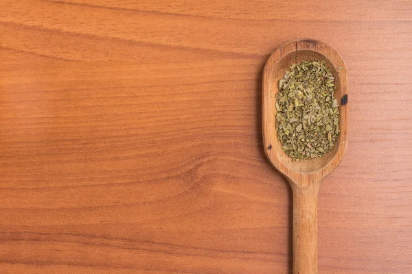 Dry Oregano into a spoon over a wooden table — Stock Photo, Image