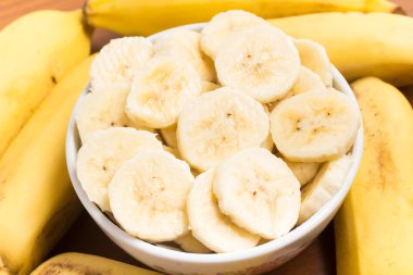 Bir kase içinde ahşap bir masa içine muz dilimleri