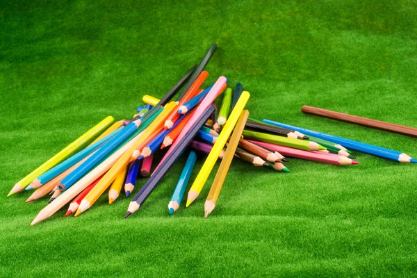 Barevné tužky roztroušených na zelené trávě — Stock fotografie