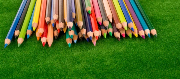 Barevné tužky roztroušených na zelené trávě — Stock fotografie
