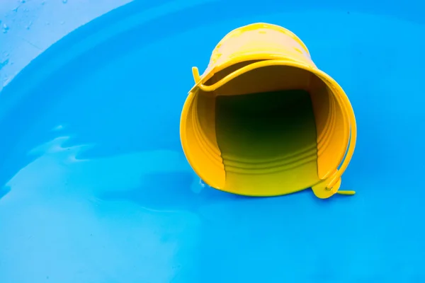 Pequeño cubo amarillo en agua en fondo azul — Foto de Stock