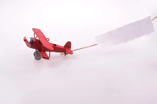 Avião voando com um papel atrás — Fotografia de Stock