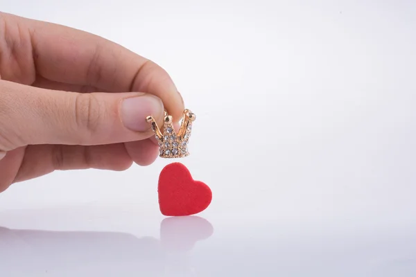 La mano sostiene la corona cerca de un corazón —  Fotos de Stock