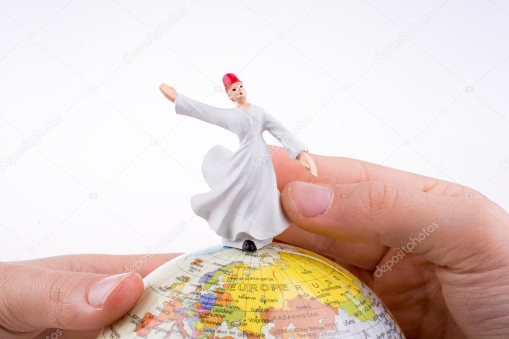 Hand holding a Dervish on a globe