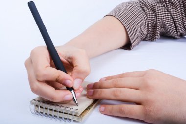 Çocuk el üstünde bir spiral defter kalemle yazma