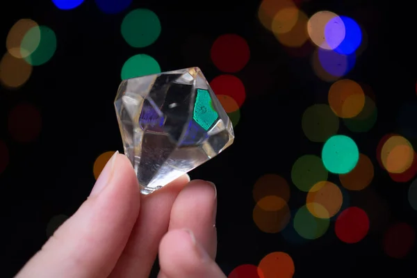 Mano Sosteniendo Diamante Transparente Sobre Fondo Con Luces Borrosas — Foto de Stock