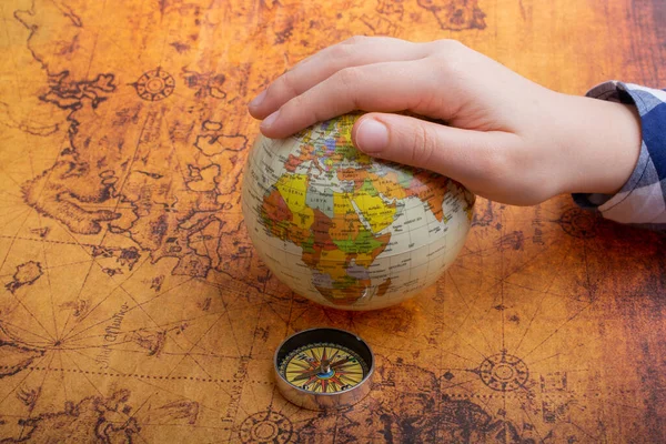 Compass on map beside a globe under hand