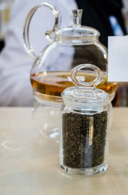 Cam çaydanlıkta demlenmiş bitki çayı ve şişede çay bitkisi.