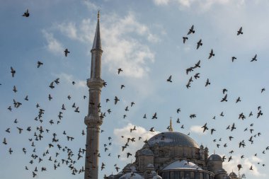 Cami minarelerinin etrafında uçan güvercinler.