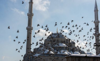 Cami minarelerinin etrafında uçan güvercinler.