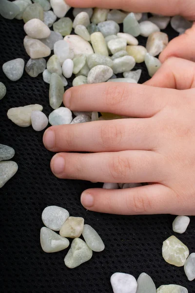 Clean stone pebbles gravels under hand on a black background