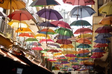 Şemsiyeler sokağın üzerinde yüzüyor güneş ışığından korunuyor