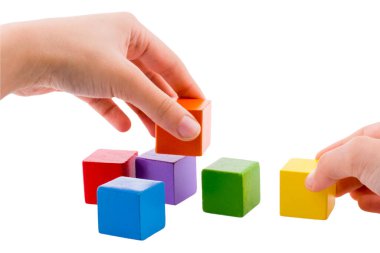 Renkli tahta bloklarla oynayan ve inşa eden eller. Erken öğrenme ve geliştirme
