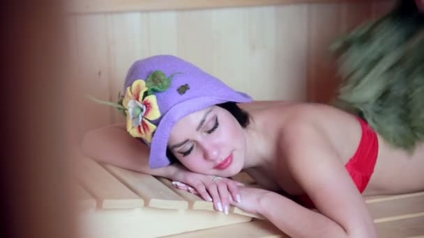 Young sexy girl sweating in the in wooden sauna. Lady hover brooms. — Stock Video