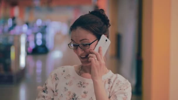 Feliz mujer de compras en el centro comercial, hablando en el teléfono inteligente . — Vídeos de Stock