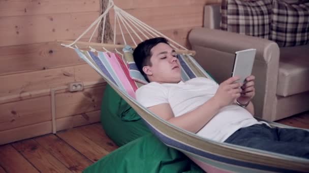 Internet homme dépendant fatigué d'être en ligne, utilisant la tablette, couché sur l'hamac . — Video