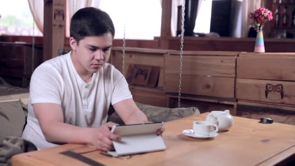 タブレット コンピューターのカフェでコーヒーを飲むと若い男. — ストック動画