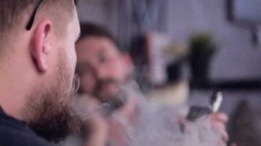 Sigara e-sigara vape konuşurken ve vaping kafede oturan iki şık genç adam.