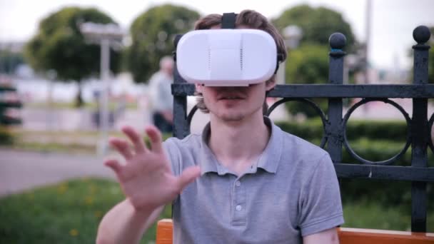 Молодой человек с 3D VR головой установлен дисплей в парке смотреть 360 фильмов, играя в виртуальные игры . — стоковое видео
