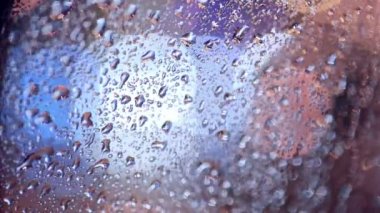 Mevsimlik arka plan trafik ışıkları bir araç penceresinde, yağmur damlaları.