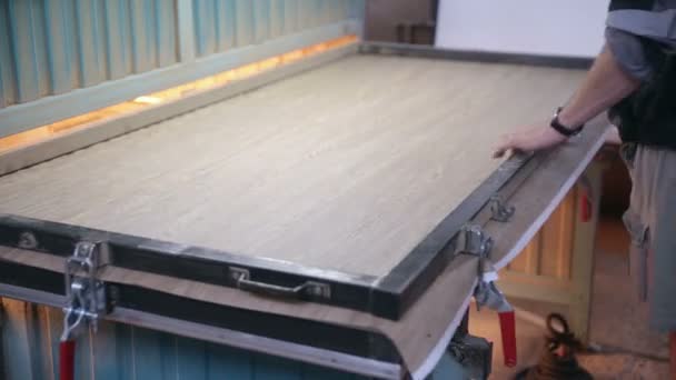 L'homme met la porte en bois dans la presse hydraulique automatisée .