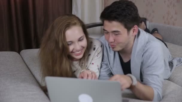 Usmívající se pár s přenosným počítačem doma. Technologie, domov, rodina koncept.