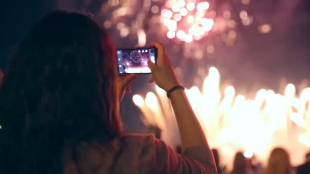 Színes tűzijáték a mobiltelefonján a forgatás felismerhetetlen nő. — Stock videók