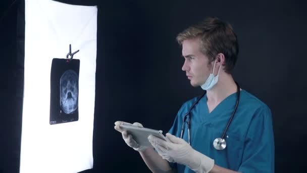 Αρσενικό ο γιατρός κατά την εργασία στην ιατρική κλινική εξέταση ακτινογραφία πλάκες της κεφαλής. — Αρχείο Βίντεο