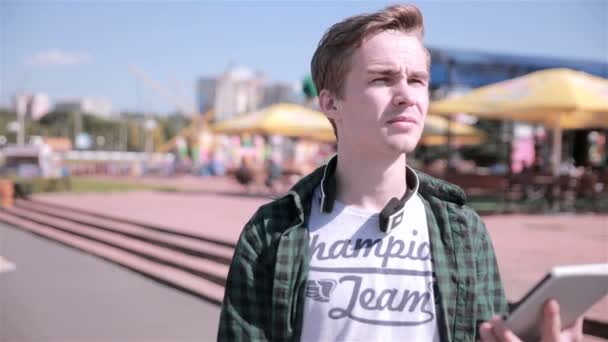 Young handsome man walking in the city with tablet, playing game. — Stock Video