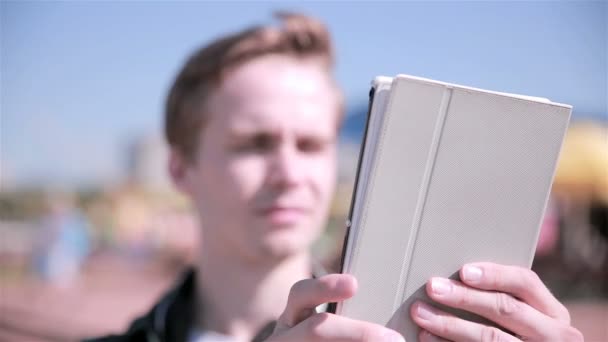 Ung man spelar Pokemon gå i staden, med hjälp av Tablet PC. — Stockvideo