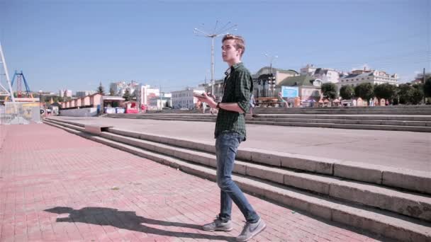 Junger Touristenmann mit Karte auf seinem Tablet zu Fuß in der Stadt. — Stockvideo