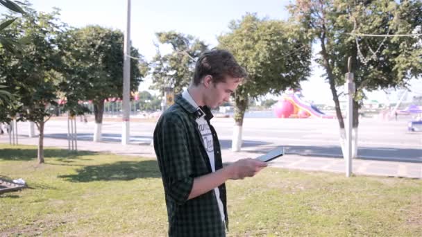 使用平板电脑的年轻时髦人在城市公园玩口袋妖怪去. — 图库视频影像