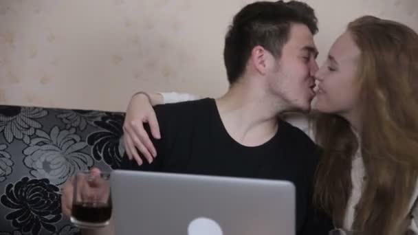 Jovem feliz casal compartilhando um laptop, beijando, sorrindo . — Vídeo de Stock