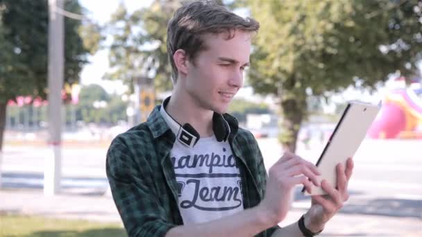 Jeune homme regardant la carte sur sa tablette, jouer Pokemon GO dans la ville . — Video