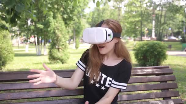 Young artistic blonde woman playing game using VR-helmet for smartphones. Modern augmented reality device. — Stock Video