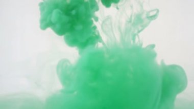 Renkli arka plan. Yeşil mürekkep suya düştü. Ağır çekim.