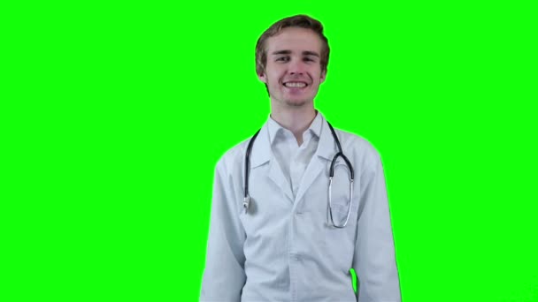 Позитивный доктор смотрит в камеру, указывает на предмет. Зеленый экран . — стоковое видео