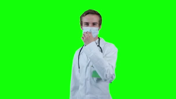 男性白人ジュニア病院医師が白衣と聴診器を身に着けています。クロマキーの背景の緑の画面. — ストック動画