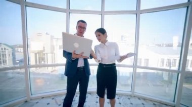 İşadamları erkek ve kadın temiz panoramik pencere yakınında modern bir ofis binasında iş projesi tartışmak. İş konsepti. Steadicam ateş.